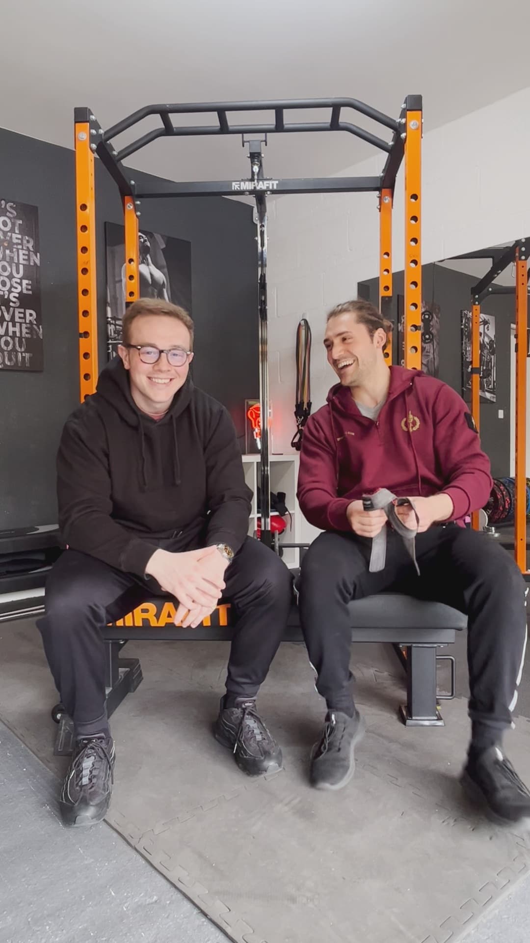 Harry and Tommy sitting together at the rack after a session at Sutton Lane Gymnasium, laughing.